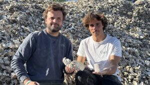 Deux jeunes hommes assis sur un tas de coquilles d'huîtres