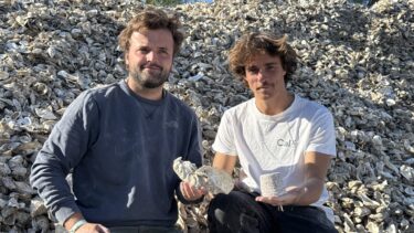 Deux jeunes hommes assis sur un tas de coquilles d'huîtres