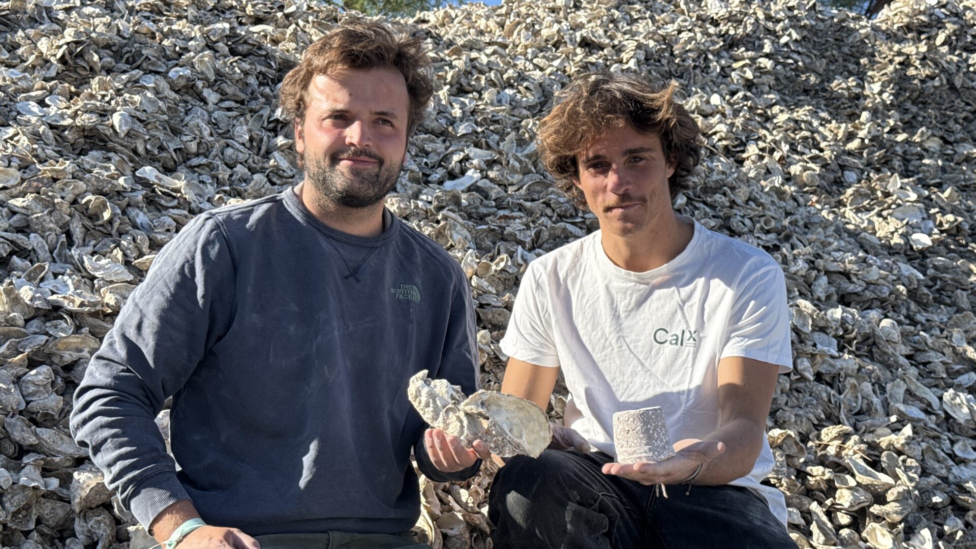 Deux jeunes hommes assis sur un tas de coquilles d'huîtres