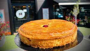 gateau basque en premier plan avec une devanture de pâtisserie en arrière plan
