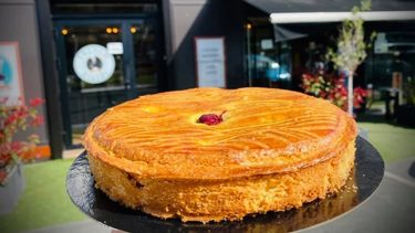 gateau basque en premier plan avec une devanture de pâtisserie en arrière plan