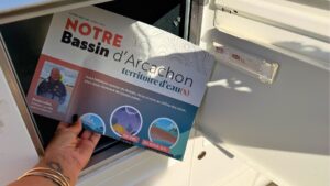 une main dans une boite aux lettres qui tient un journal où il est écrit : le siba chez vous territoire d'eaux