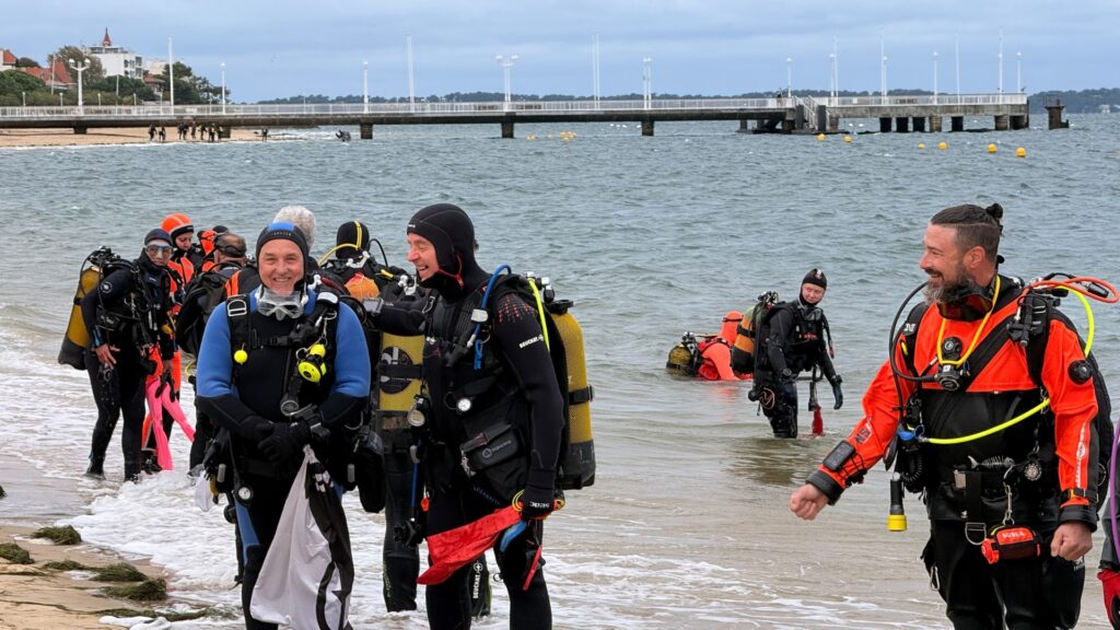 plongeurs en tenue au bord de la plage d'arcachon avec la jetée thiers en arrière plan