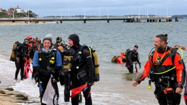 plongeurs en tenue au bord de la plage d'arcachon avec la jetée thiers en arrière plan