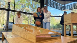 1 femme et deux enfants dans l'eau'ditorium de Biganos en train de consulter un document, un module en bois au premier plan